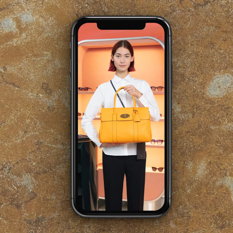 Women holding a Mulberry bag displayed on a mobile device